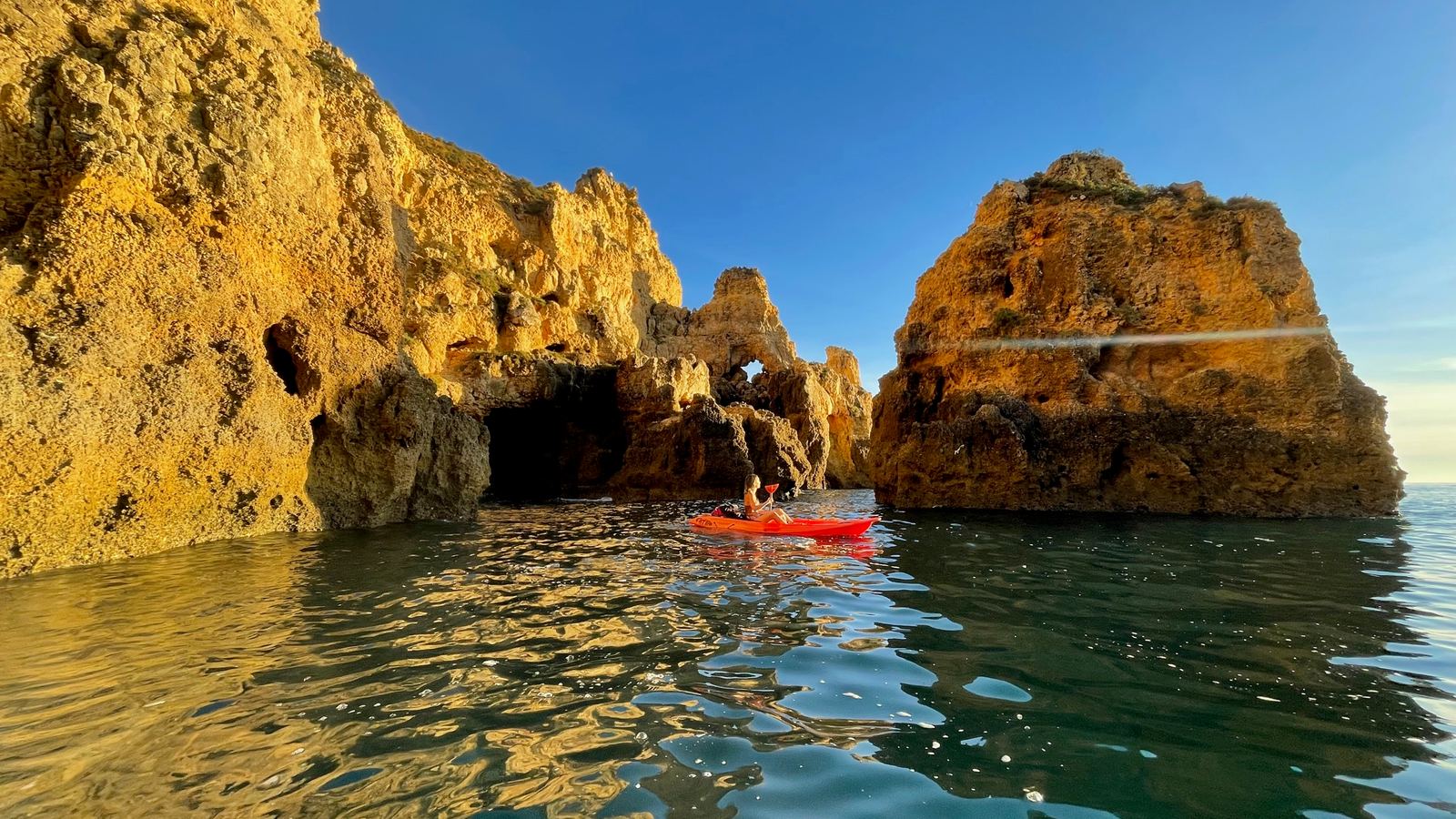 Kayaker paddling between the golden sea stacks and caves of Ponta da Piedade, Lagos