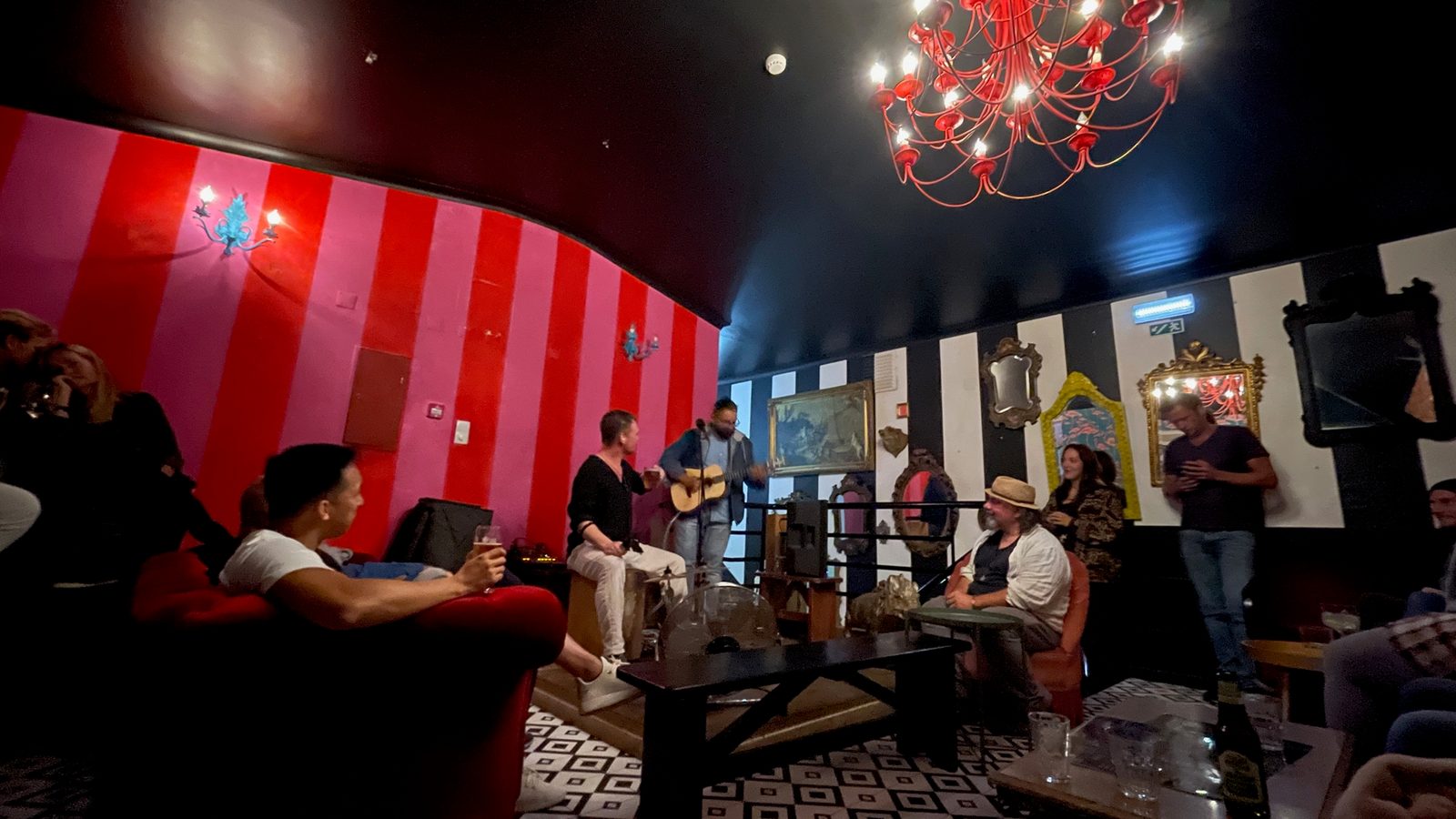 Live acoustic music in a bar with red striped walls and a red chandelier at Ol' Bastards, Lagos